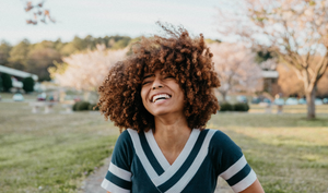 Woman with natural curly hair smiling on a breezy day